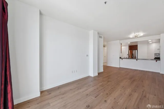 a view of a big room with wooden floor and a kitchen
