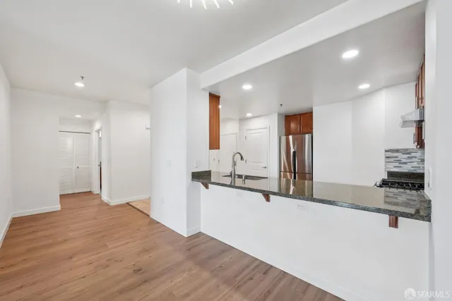 a kitchen with stainless steel appliances kitchen island granite countertop a refrigerator and a sink