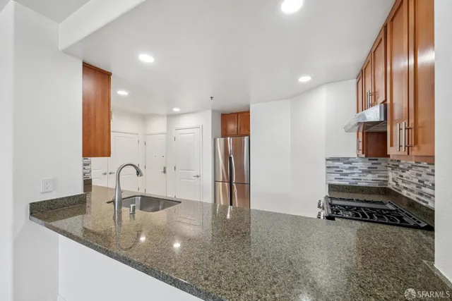 a kitchen with stainless steel appliances granite countertop a sink and a refrigerator