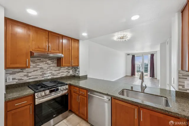 a kitchen with granite countertop stainless steel appliances a sink stove and cabinets