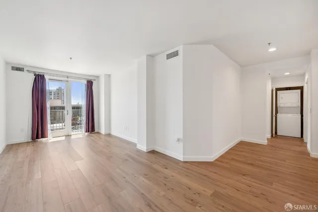 a view of an empty room with glass door and wooden floor