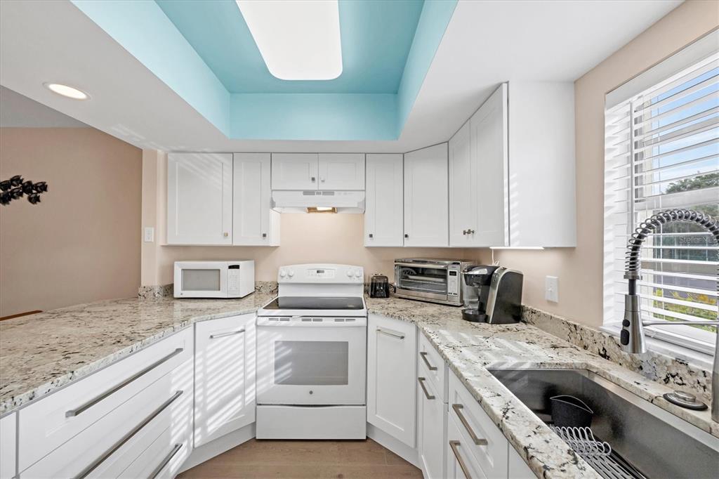 1531 Placida Road, Unit 4102 Englewood, FL 34223 - Photo 18 of 55 a kitchen with granite countertop a sink a stove a washer and dryer