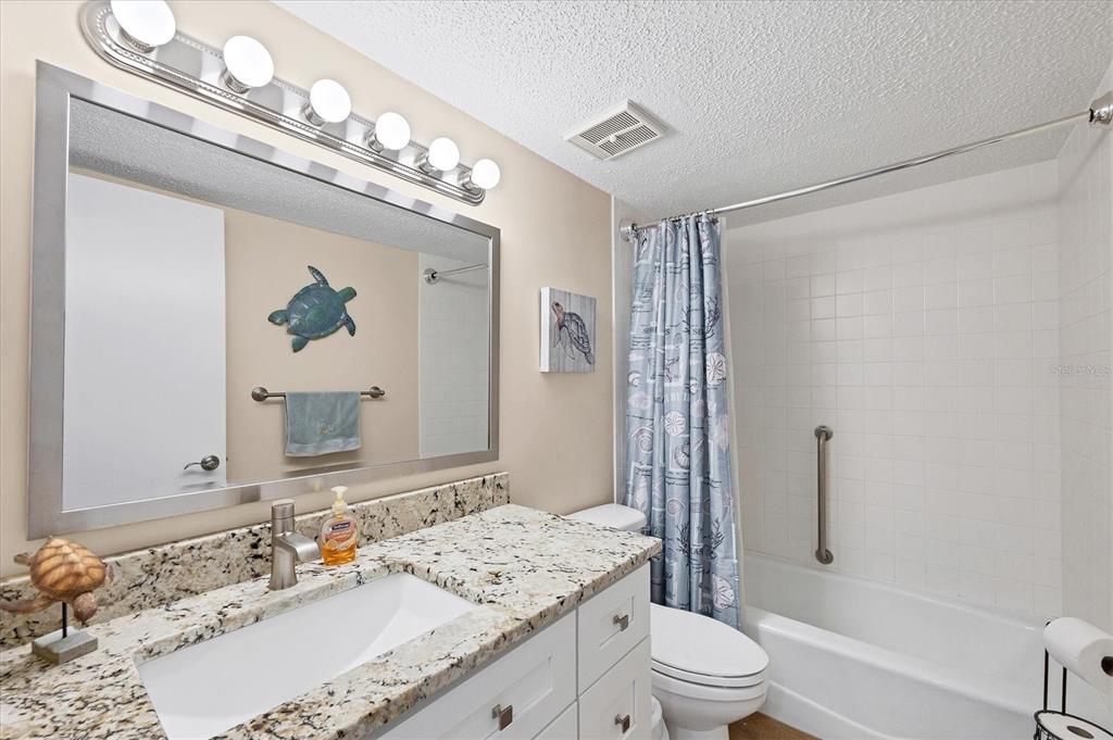 1531 Placida Road, Unit 4102 Englewood, FL 34223 - Photo 31 of 55 a bathroom with a granite countertop sink a toilet a mirror a vanity and shower
