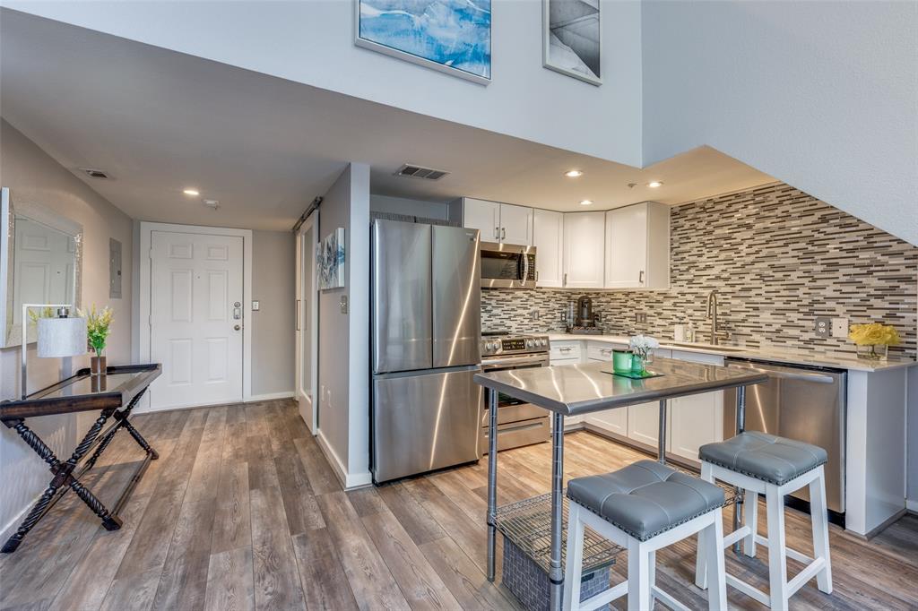 5111 Manett Street, Unit 208 Dallas, TX 75206 - Photo 2 of 13 a kitchen with stainless steel appliances kitchen island granite countertop a dining table chairs and a refrigerator