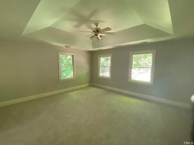 an empty room with windows and fan