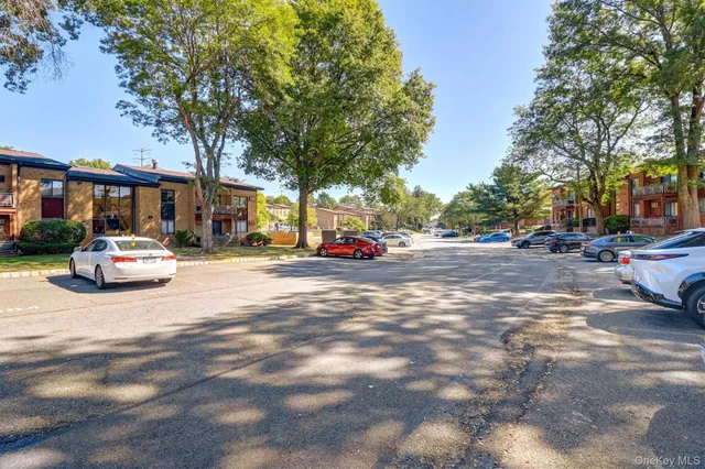 a view of road with card parked on side and retail shops