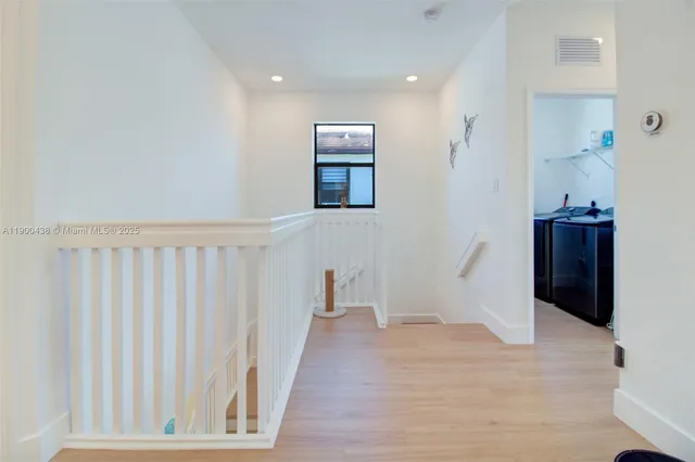 a view of a hallway with wooden floor and a bathroom