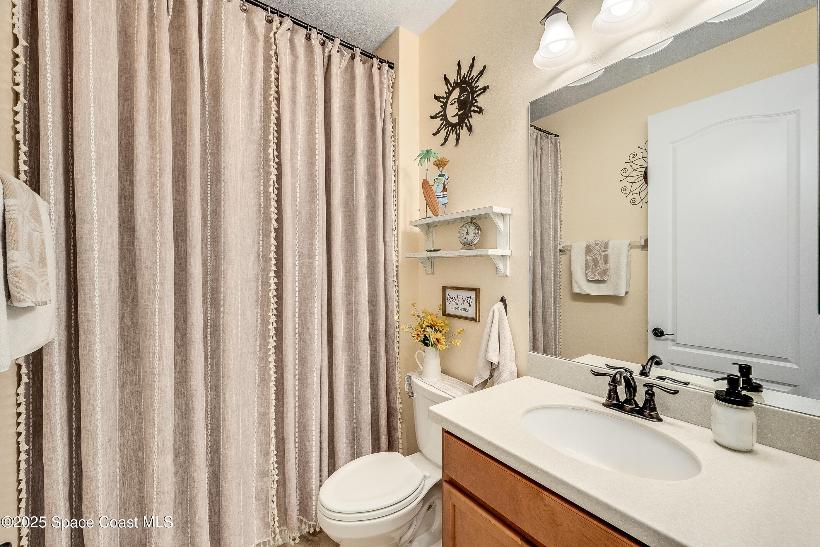 5738 Tamarac Drive Melbourne, FL 32940 - Photo 18 of 27 a bathroom with a sink a toilet and shower curtain