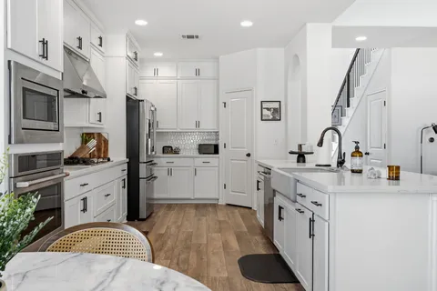 a large white kitchen with stainless steel appliances sink stove and cabinets