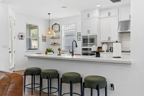 a kitchen with stainless steel appliances granite countertop a table and chairs in it