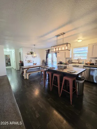a dining room with kitchen island granite countertop wooden floor and a sink
