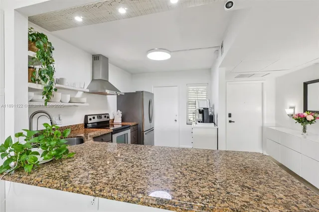 a kitchen with stainless steel appliances kitchen island granite countertop a sink stove and refrigerator