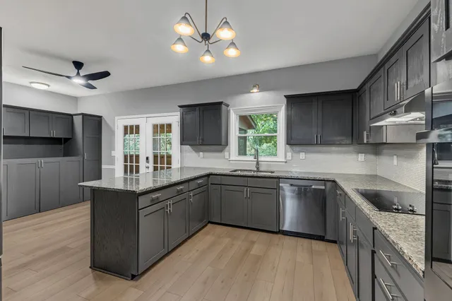 a kitchen with stainless steel appliances granite countertop cabinets a sink a stove a refrigerator and island with wooden floor