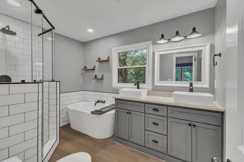 a bathroom with a tub a sink and mirror