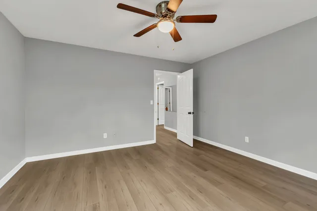 an empty room with wooden floor and a ceiling fan