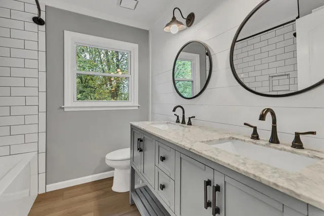 a bathroom with a granite countertop double vanity sink and a mirror