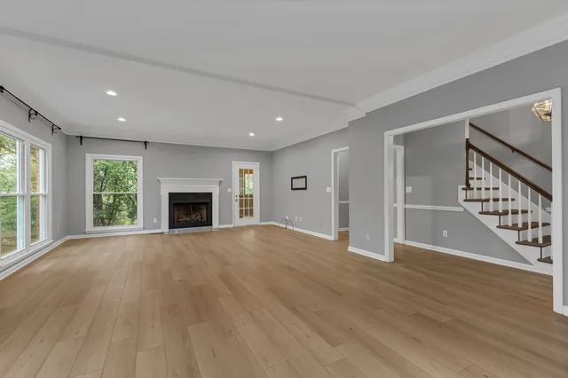 an empty room with wooden floor fireplace and windows