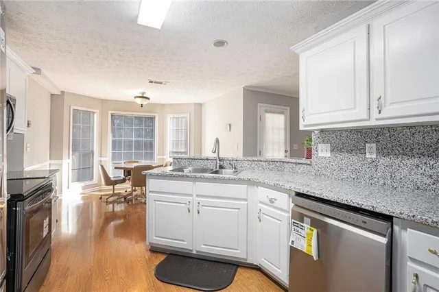 a kitchen with granite countertop a sink a stove cabinets and wooden floor
