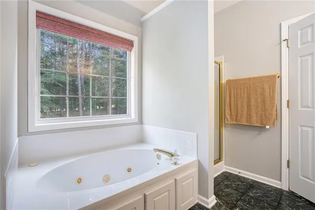 a bathroom with a tub a window and a shower