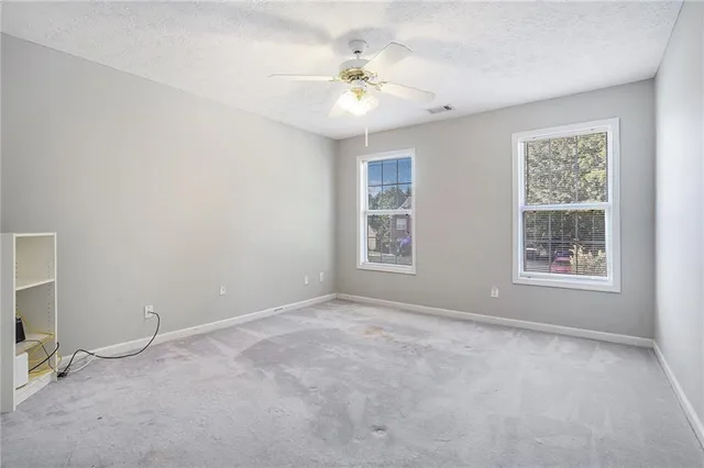 an empty room with windows and chandelier fan