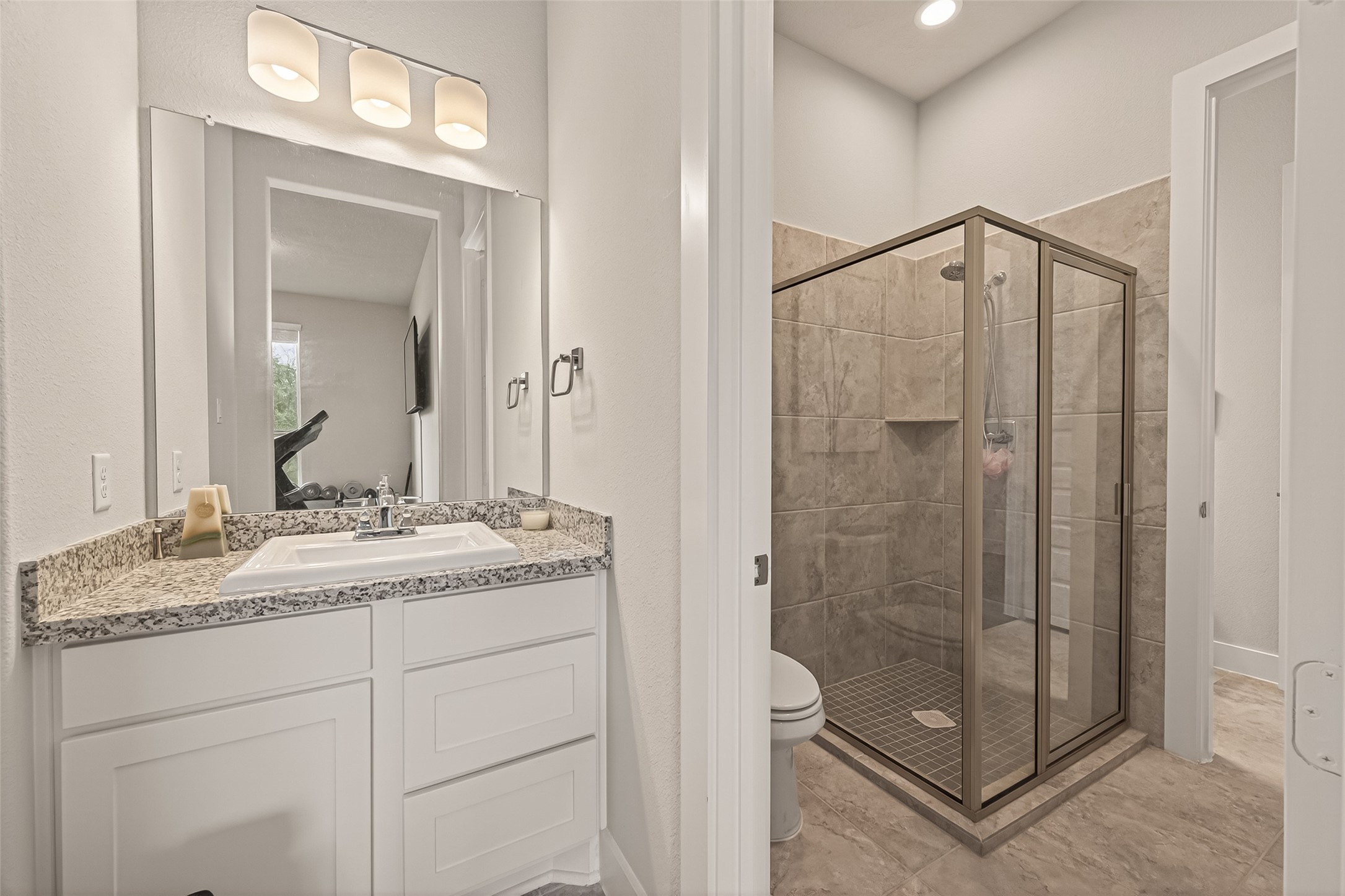 1815 Brea Rdg Trail Katy, TX 77494 - Photo 19 of 43 This bathroom features a modern design with a granite-topped vanity, large mirror, and a glass-enclosed shower. The neutral-toned tiles add a touch of elegance and the room is well-lit with contemporary fixtures.