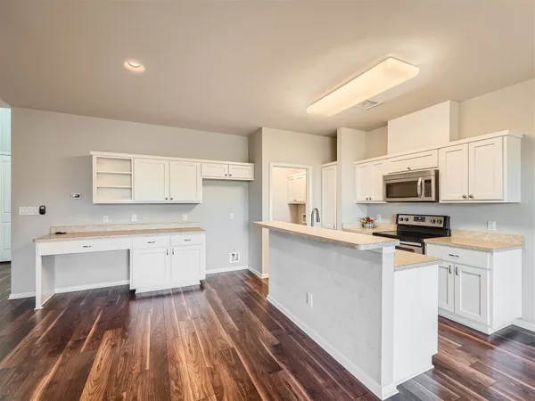 a kitchen with stainless steel appliances a stove top oven a sink cabinets and wooden floor