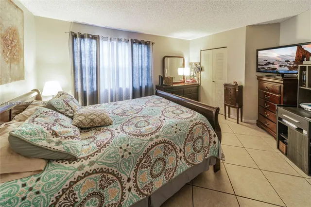 a bedroom with a bed a television and large window