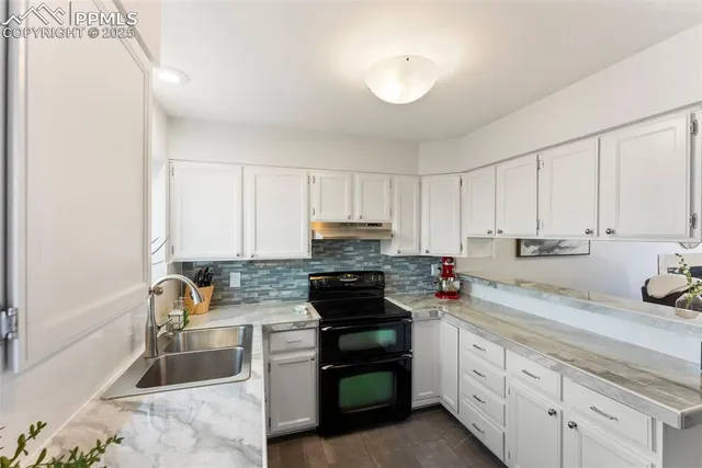 a kitchen with granite countertop a stove sink and cabinets