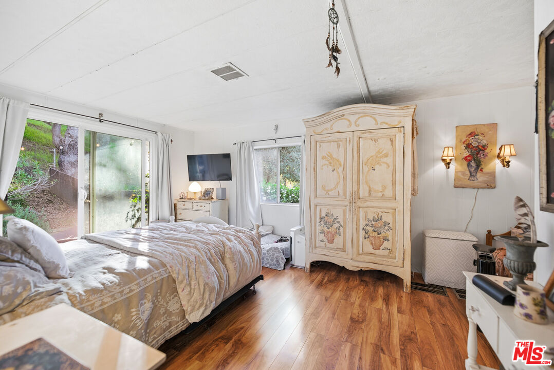 1667 Las Virgenes Canyon Road, Unit 5 Calabasas, CA 91302 - Photo 18 of 36 a bedroom with a bed a flat screen tv and a window