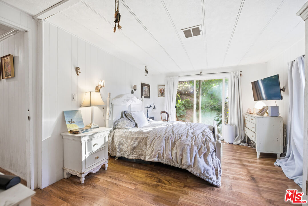 1667 Las Virgenes Canyon Road, Unit 5 Calabasas, CA 91302 - Photo 19 of 36 a bedroom with a bed and wooden floor