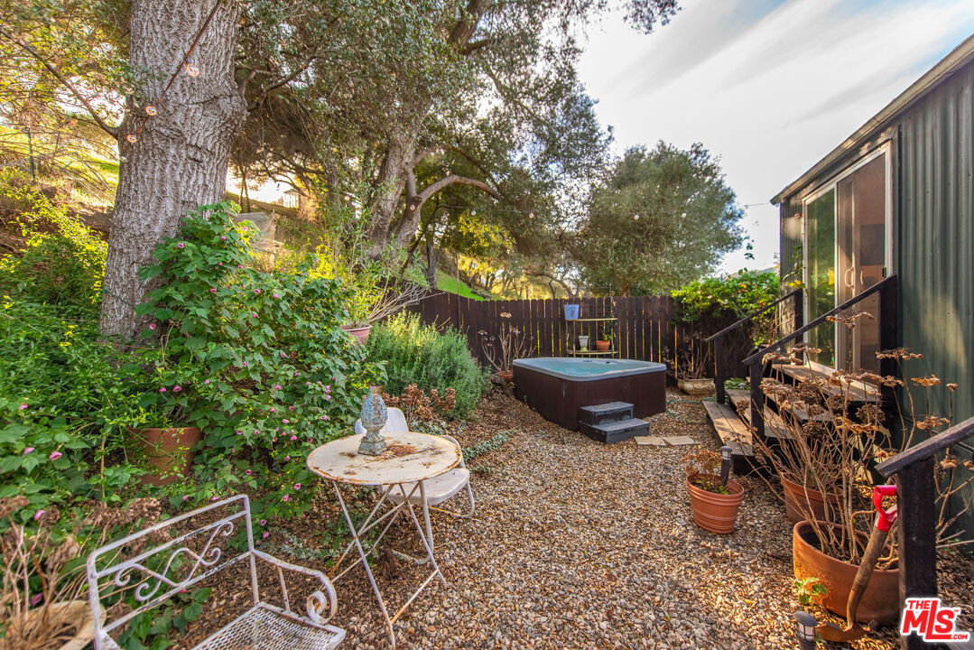 1667 Las Virgenes Canyon Road, Unit 5 Calabasas, CA 91302 - Photo 3 of 36 a view of a backyard with table and chairs potted plants and a large tree