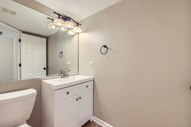 a bathroom with a toilet a sink a mirror a vanity and window