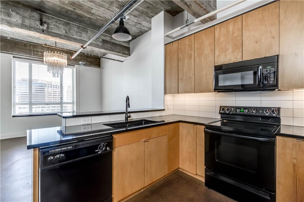 710 Colorado Street, Unit G9 Austin, TX 78701 - Photo 4 of 25 A contemporary kitchen space boasts exposed concrete ceilings and ample natural light through expansive windows.