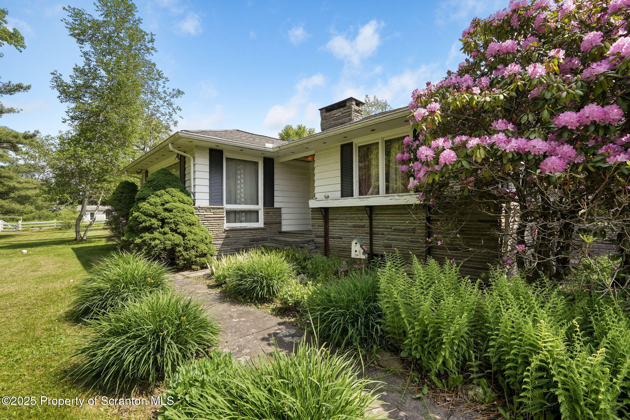 17512 Highway 267 Montrose, PA 18801 - Photo 27 of 27 a front view of a house with lots of flower and trees