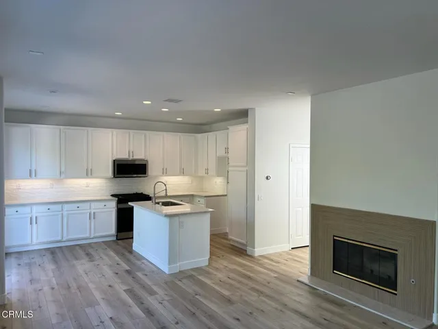 a kitchen with stainless steel appliances granite countertop a stove top oven a sink dishwasher and a refrigerator with wooden floor