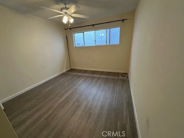 an empty room with wooden floor and a ceiling fan