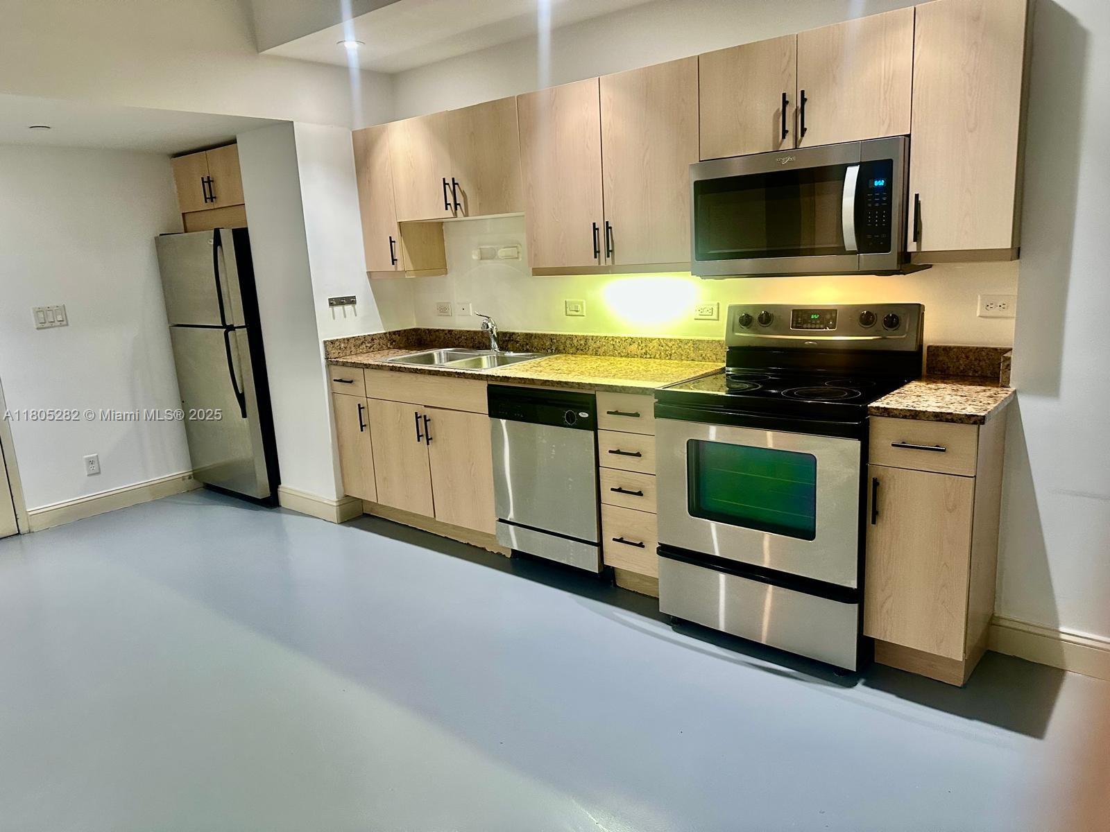 a kitchen with stainless steel appliances granite countertop a stove a sink and a microwave