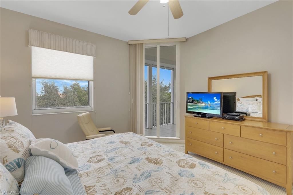 450 Launch Circle, Unit 404 Naples, FL 34108 - Photo 11 of 32 a bedroom with a bed and a television