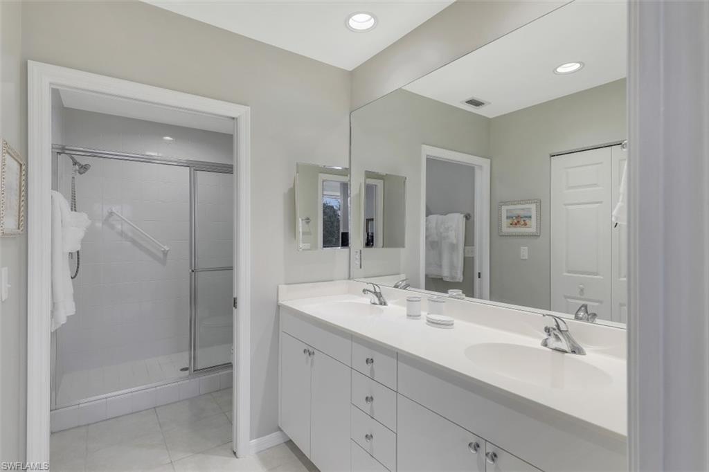 450 Launch Circle, Unit 404 Naples, FL 34108 - Photo 12 of 32 a bathroom with a double vanity sink mirror and shower