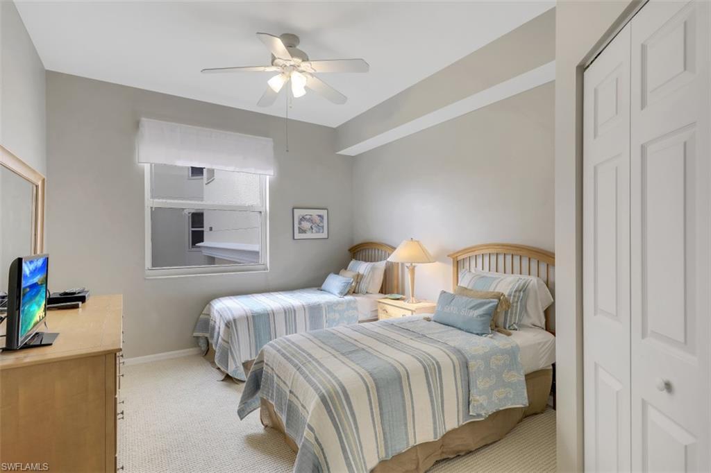 450 Launch Circle, Unit 404 Naples, FL 34108 - Photo 15 of 32 a bedroom with a bed and a chandelier