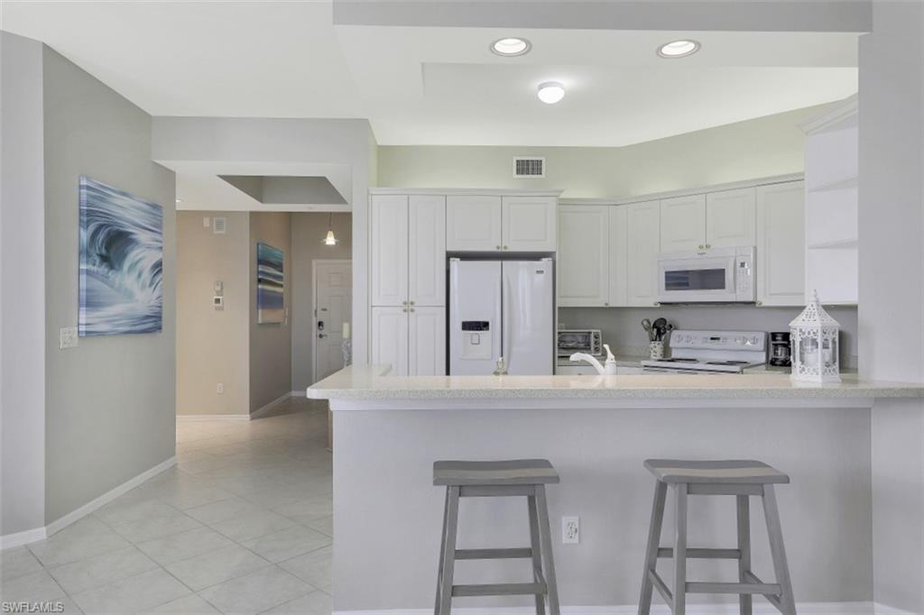 450 Launch Circle, Unit 404 Naples, FL 34108 - Photo 6 of 32 a kitchen with stainless steel appliances a refrigerator and cabinets