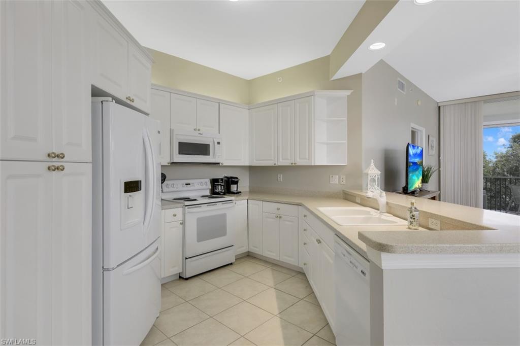 450 Launch Circle, Unit 404 Naples, FL 34108 - Photo 7 of 32 a kitchen with white cabinets and white appliances