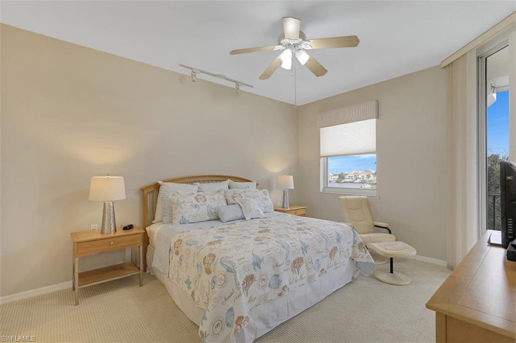 450 Launch Circle, Unit 404 Naples, FL 34108 - Photo 10 of 32 a bedroom with a bed and a chandelier