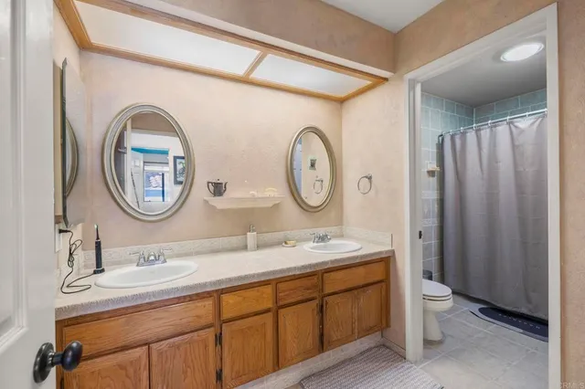 a bathroom with a toilet a double vanity sink and a mirror