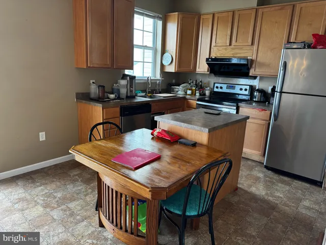 a kitchen with stainless steel appliances granite countertop a refrigerator a stove a sink dishwasher and microwave