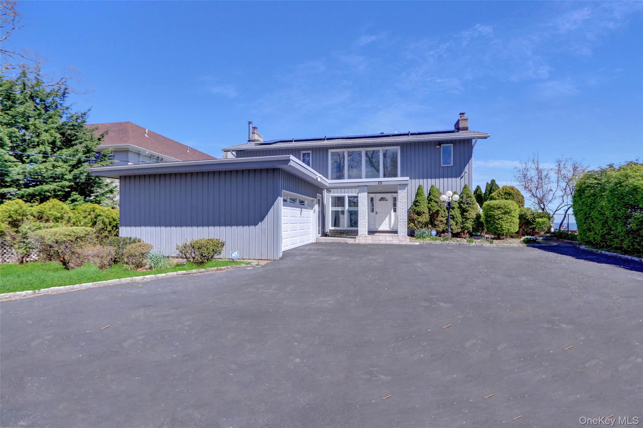 View of front of property with a chimney, asphalt driveway, solar panels, and an attached garage