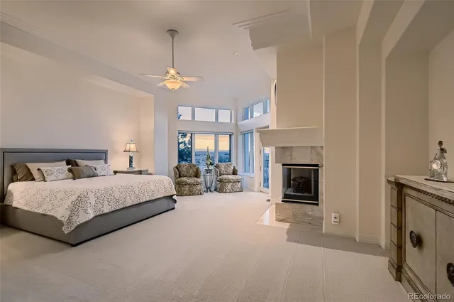 a spacious bedroom with a bed a fireplace and a chandelier