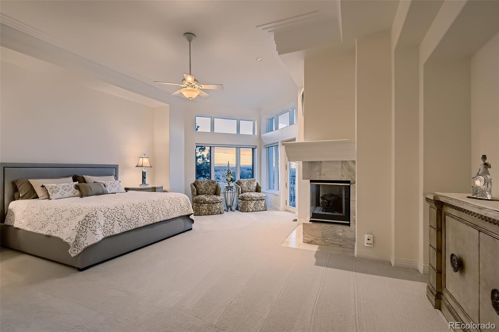 8561 Colonial Drive Lone Tree, CO 80124 - Photo 16 of 50 a spacious bedroom with a bed a fireplace and a chandelier