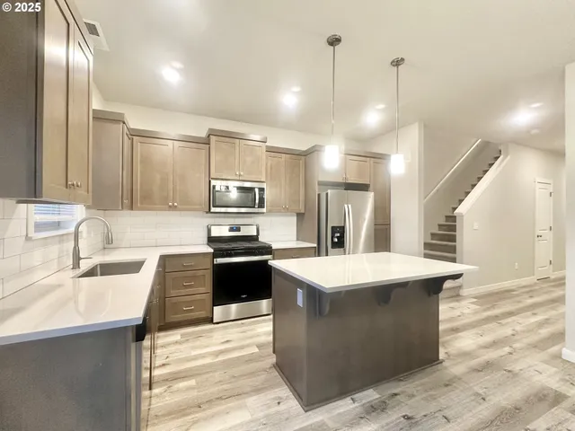 a large kitchen with kitchen island a sink stainless steel appliances and cabinets