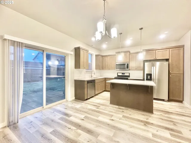 a large kitchen with kitchen island a sink stainless steel appliances and a chandelier